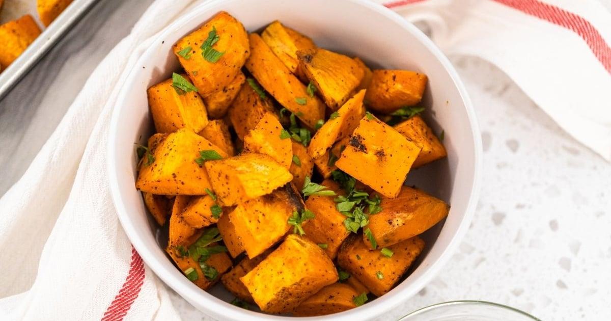 Cubos de batata-doce dourados e crocantes na cesta da airfryer com ervas e páprica