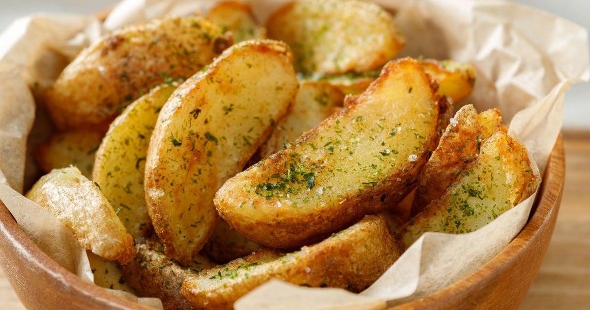 Gomos de batata rústica dourados e estaladiços na cesta da airfryer temperados com ramos de alecrim