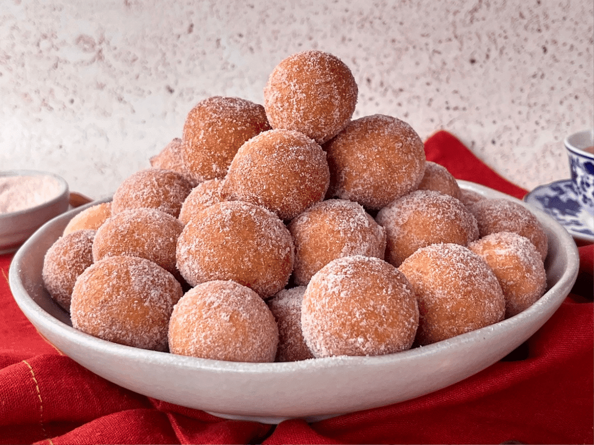 Bolinhos de chuva dourados e polvilhados com açúcar e canela em uma tigela aconchegante