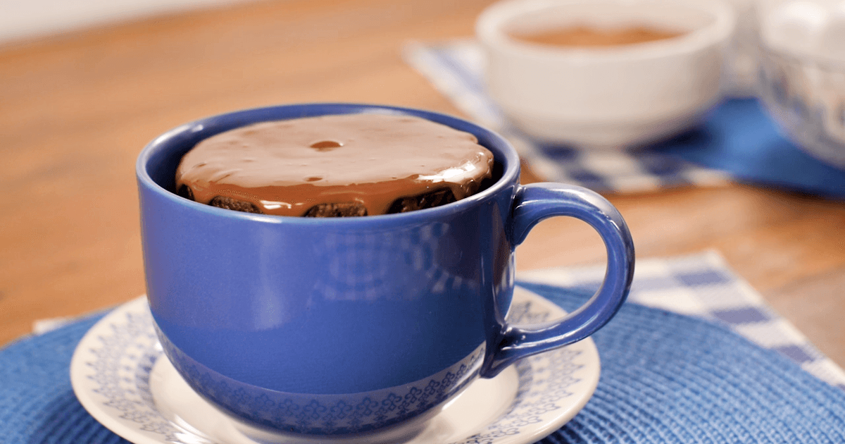 Bolo de caneca de chocolate quentinho transbordando com calda cremosa de brigadeiro