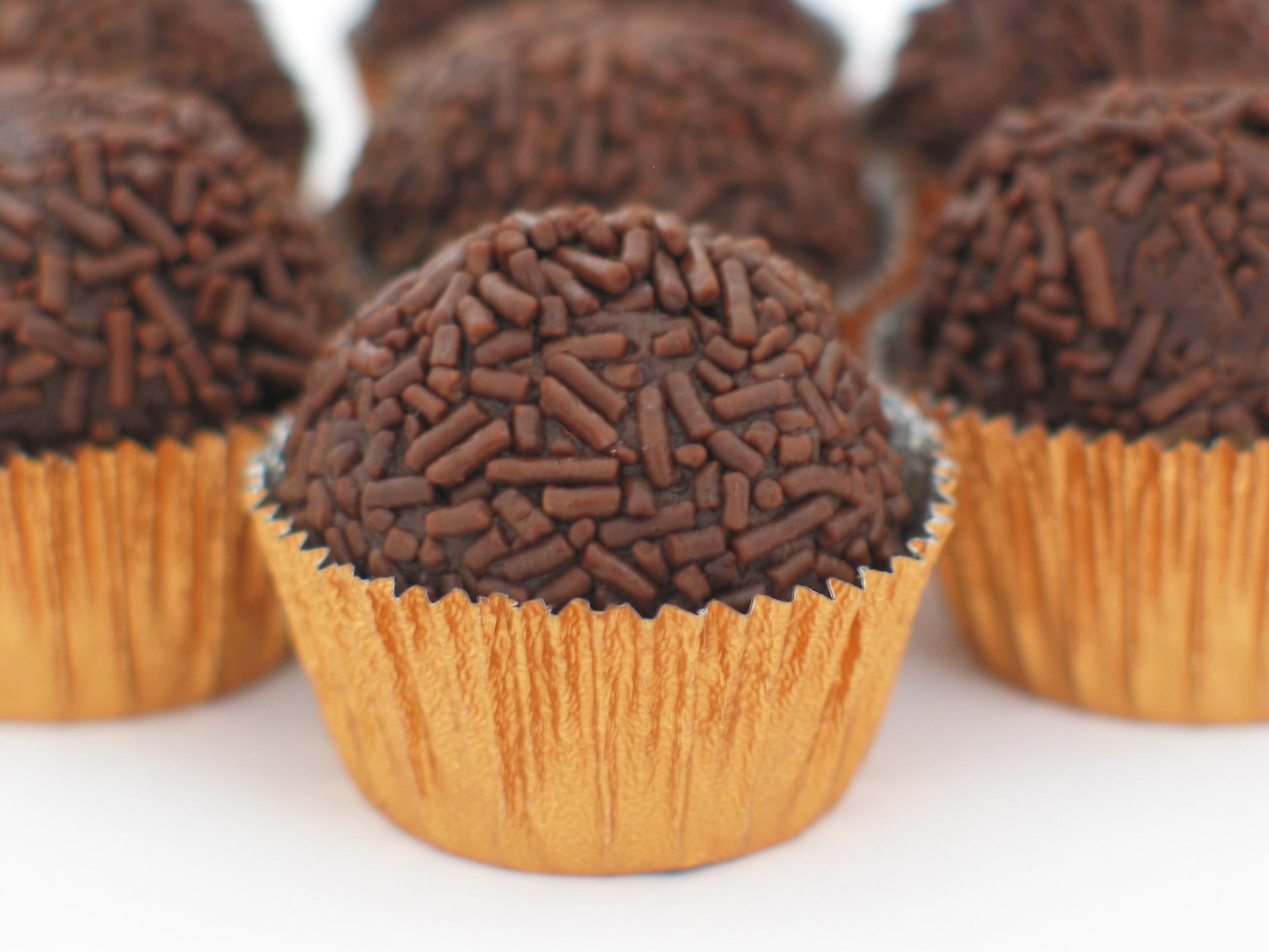 Glistening chocolate brigadeiro truffles rolled in sprinkles in paper cups