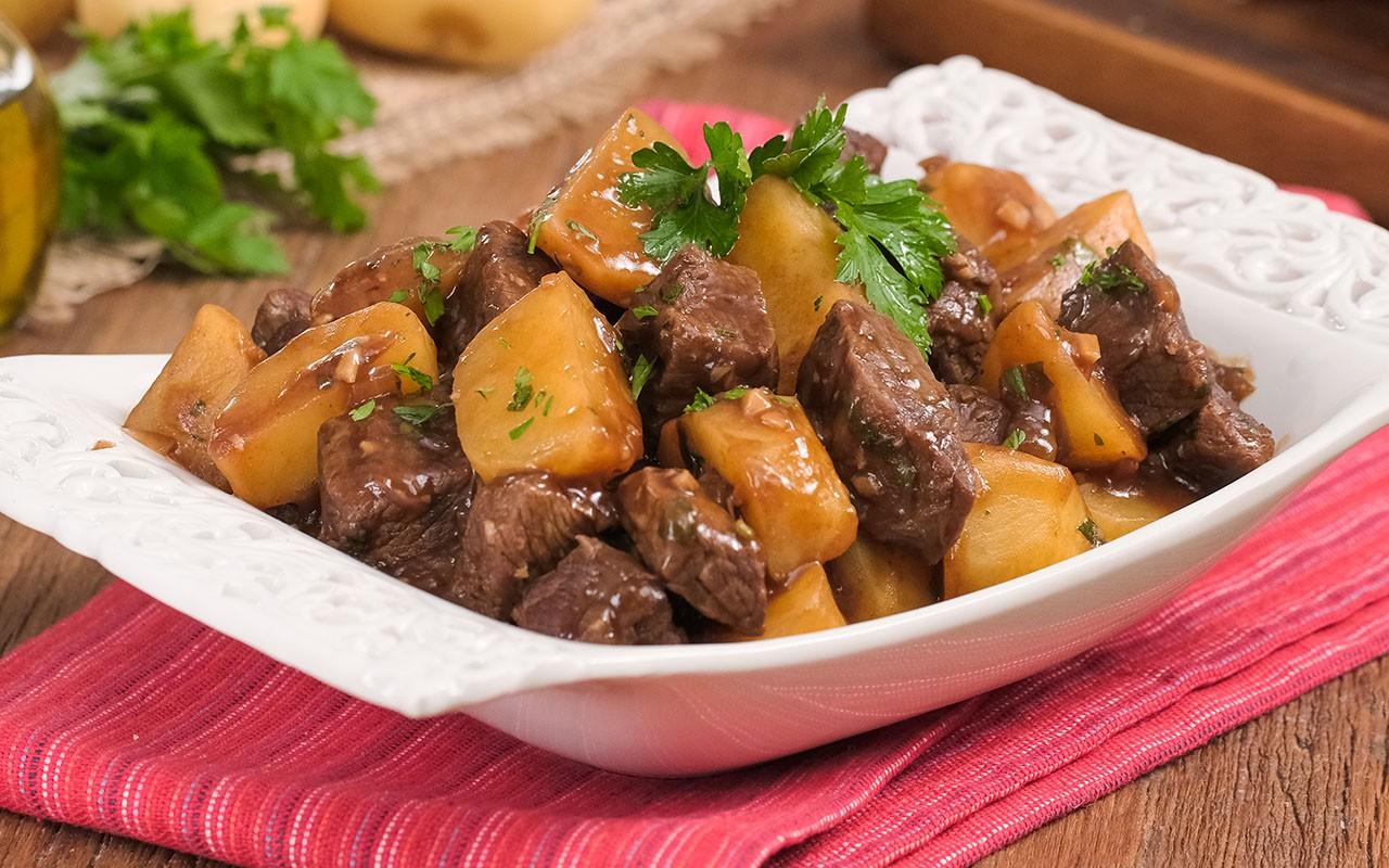 Prato fumegante de carne de panela com batatas macias regadas por molho espesso e cheiro-verde