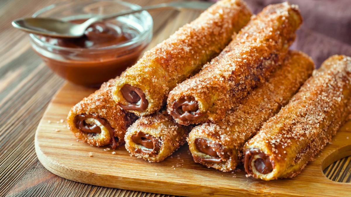 Rolinhos dourados e crocantes de churros fit polvilhados com canela e açúcar recheados de doce de leite