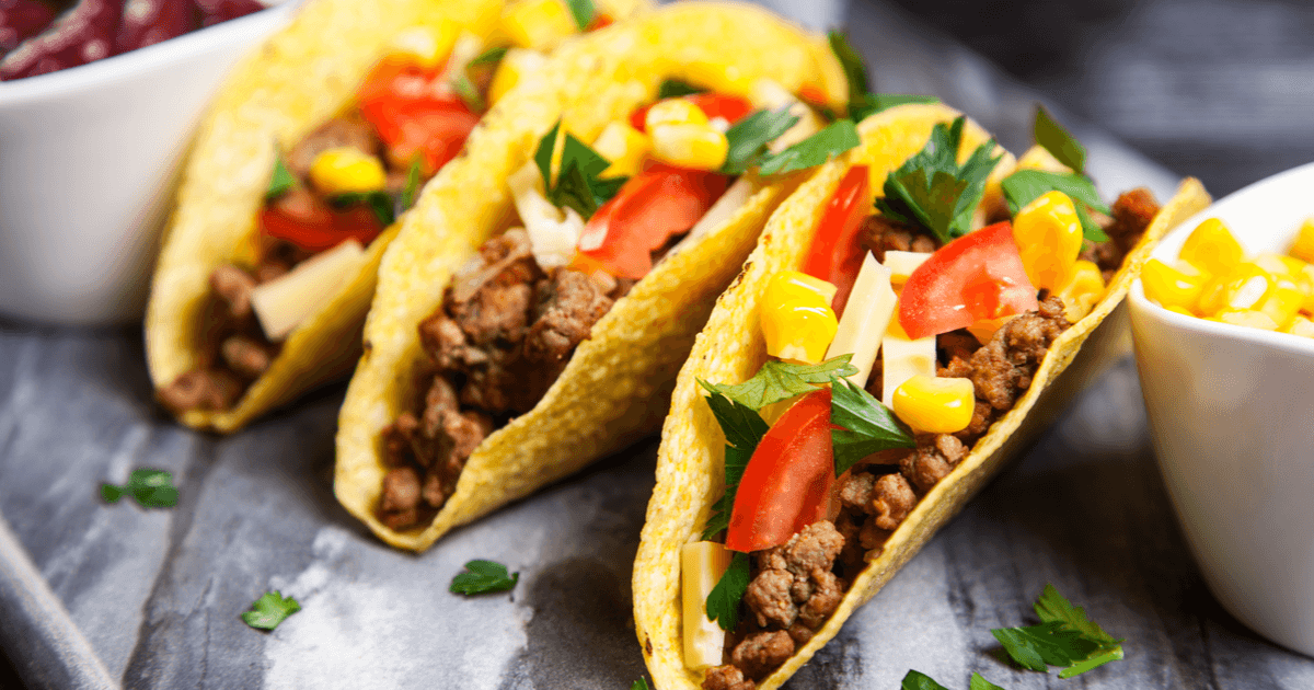 Tacos mexicanos artesanais recheados com carne apimentada, guacamole fresco, tomates e queijo derretido